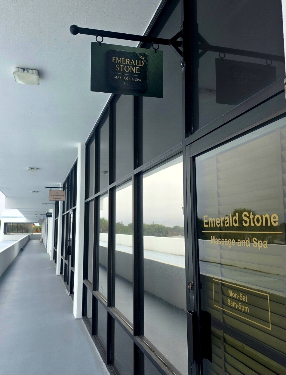 Emerald Stone Massage & Spa hallway entrance with hanging sign at Suite 104